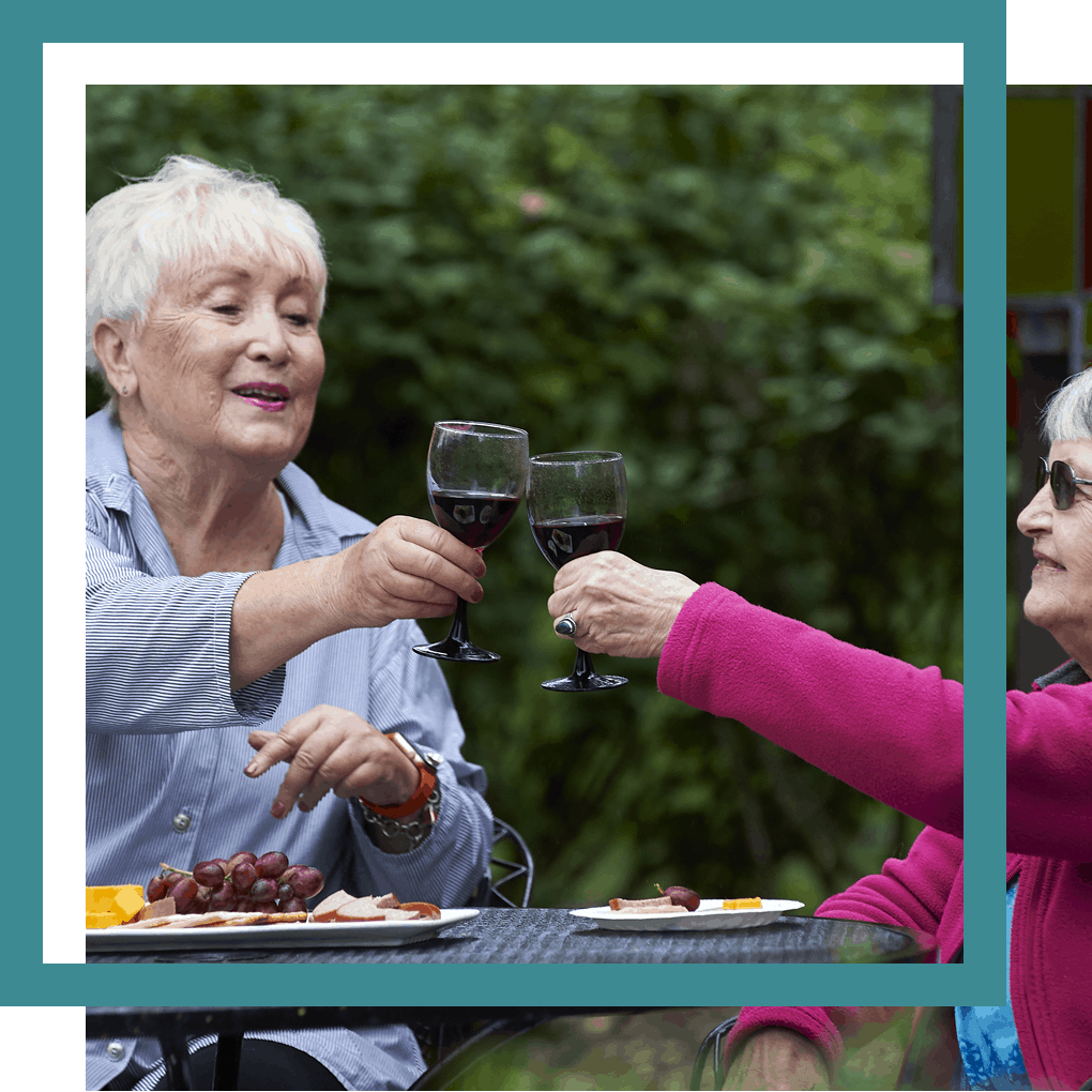 two older women toasting red wine and eating dinner