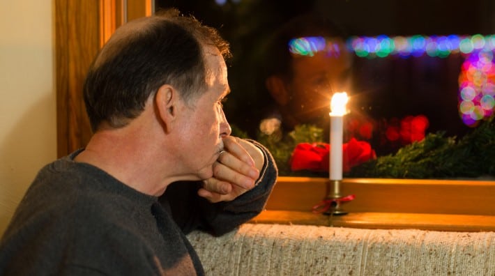 Older man looking out of window decorated for the holidays