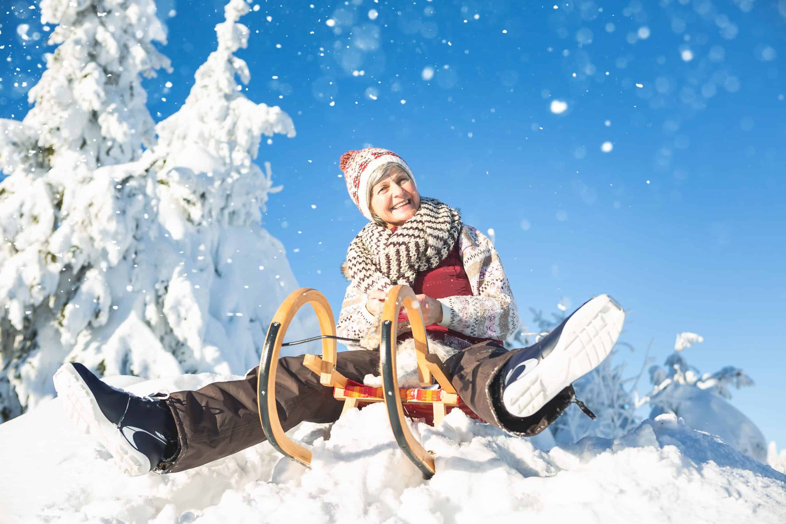 senior lady on sled in snow